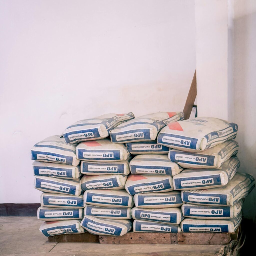 A stack of bags of cement neatly arranged in an indoor warehouse environment.