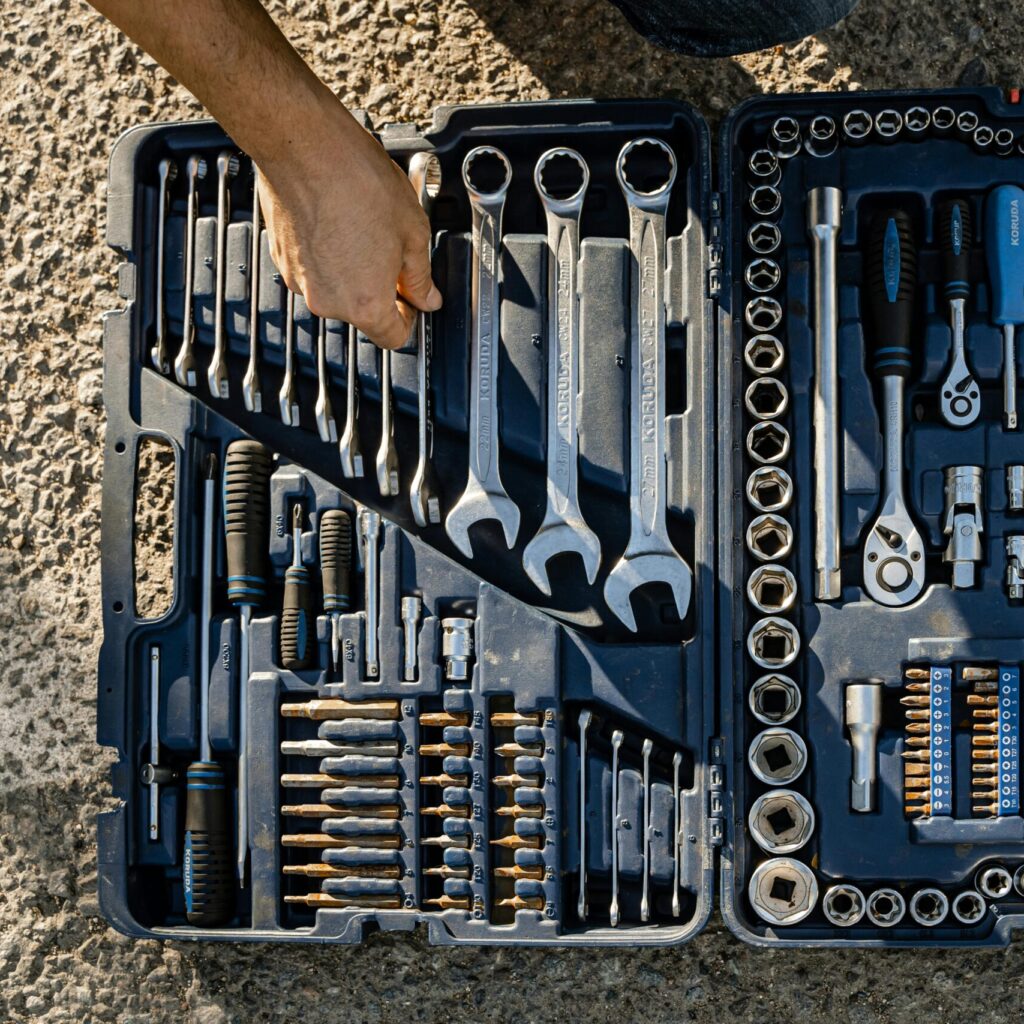 Open toolkit with assorted hand tools, including wrenches and pliers, captured outdoors.