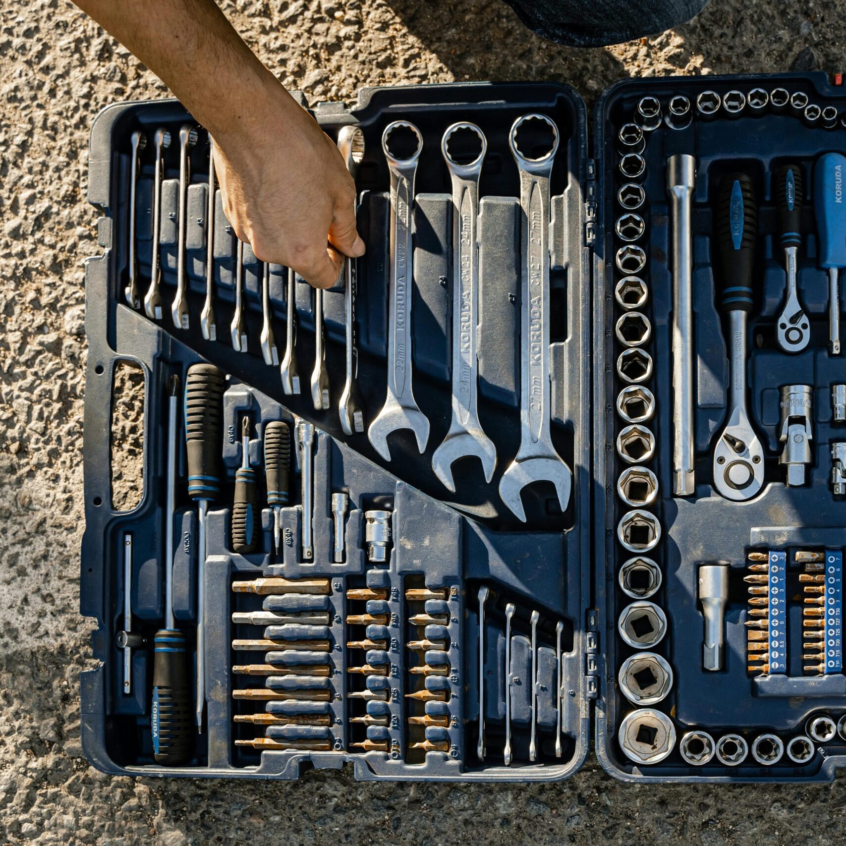 Open toolkit with assorted hand tools, including wrenches and pliers, captured outdoors.